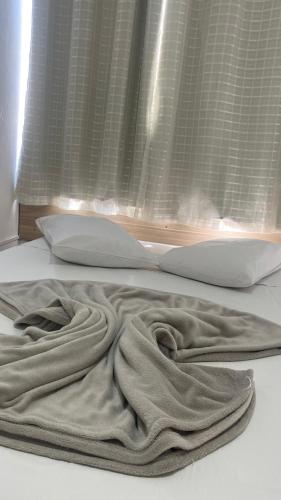 a blanket laying on a bed in front of a window at Hotel LENA in São Luiz Gonzaga