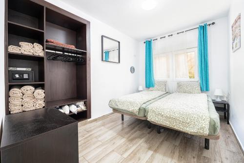 Un dormitorio con una cama y una ventana con cortinas azules. en FRUCT Pirata Beach, en Maspalomas