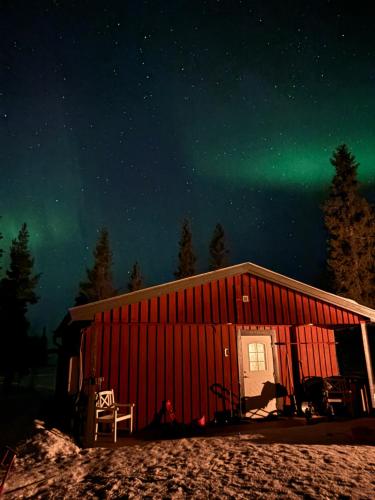 a cabin with the aurora in the night sky at Camp Caroli Family House in Jukkasjärvi