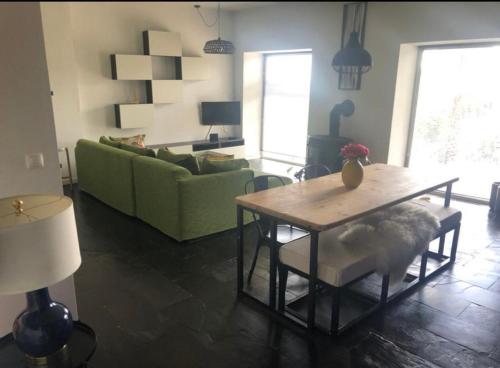 ein Wohnzimmer mit einem Tisch und einer grünen Couch in der Unterkunft Ola Bella Vista in Figueiró dos Vinhos