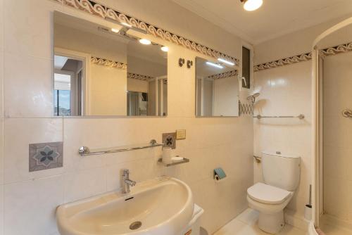 a white bathroom with a sink and a toilet at Serenity suite in Patalavaca