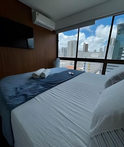a bedroom with a large white bed with a large window at Flat Luxo Boa Viagem Perto da Praia e Shopping Recife in Recife