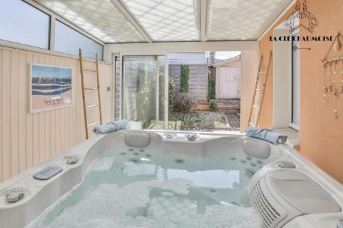 una grande vasca da bagno in una stanza con una grande finestra di Villa LS - Agreable Villa avec piscine et jacuzzi a Les Sables-dʼOlonne