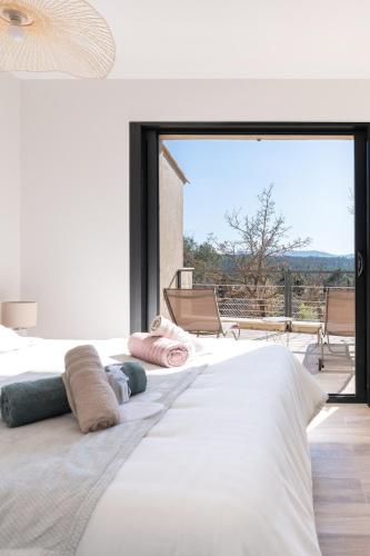 une chambre avec un grand lit avec une grande fenêtre dans l'établissement Maison paisible au pied de la Sainte Victoire Idéale pour un séjour en famille ou entre amis, à Beaurecueil