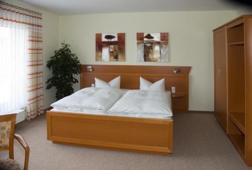 ein Schlafzimmer mit einem Bett mit weißen Kissen in der Unterkunft Hotel Zur Wildtränke in Spremberg
