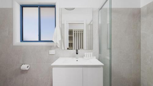 Un baño blanco con lavabo y ducha. en Coastal Hideaway - Water Views and Walk To The Beach, en Corlette
