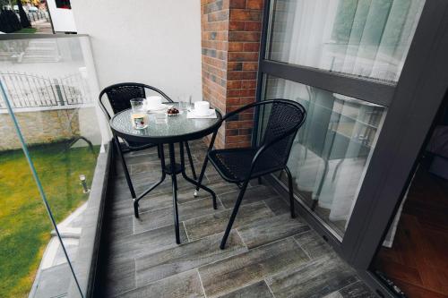 a small table and chairs on a balcony with a window at Elysium House in Truskavets