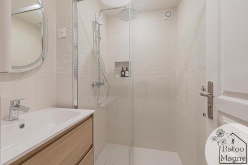une salle de bain blanche avec une douche et un lavabo dans l'établissement Un Rêve Bleu d'Aladin - Escale à Disneyland Paris, à Magny-le-Hongre