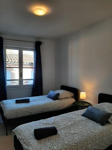 a bedroom with two beds and a window at Le beau 25 République in Montauban