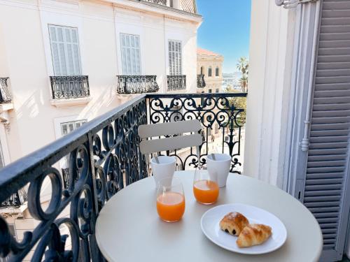 - une table avec deux verres de jus d'orange et des biscuits sur un balcon dans l'établissement Meynadier 12B, à Cannes