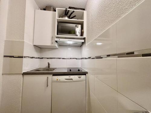 une petite cuisine avec des armoires blanches et un évier dans l'établissement Studio divisible cosy, 4 pers, skis aux pieds - FR-1-353-128, à La Plagne Tarentaise