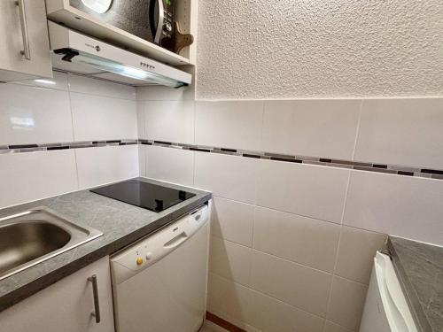 - une petite cuisine blanche avec un évier et un comptoir dans l'établissement Studio divisible cosy, 4 pers, skis aux pieds - FR-1-353-128, à La Plagne Tarentaise