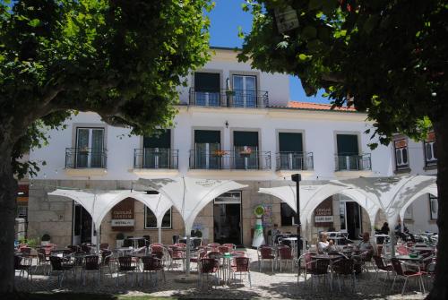 a building with tables and chairs in front of it at Hotel Covilhã Jardim in Covilhã