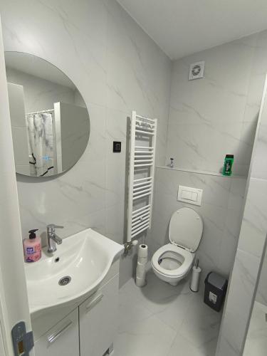 a white bathroom with a sink and a toilet at Apartman Vanja in Doboj