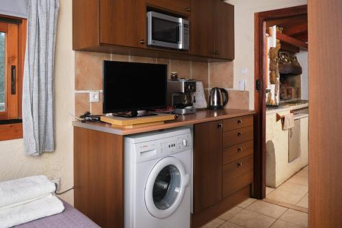 a kitchen with a washing machine and a microwave at theVotsalo Eco house in Agios Padeleimon