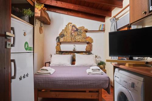 a small room with a bed and a tv at theVotsalo Eco house in Agios Padeleimon