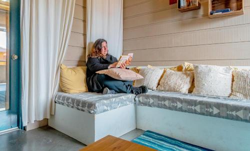 a woman sitting on a couch reading a book at Arbors at Island Landing Hotel & Suites in Pigeon Forge