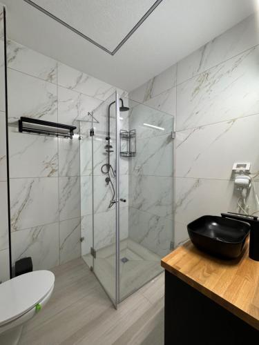a bathroom with a glass shower with a black toilet at Villa Alba in Majdal Shams