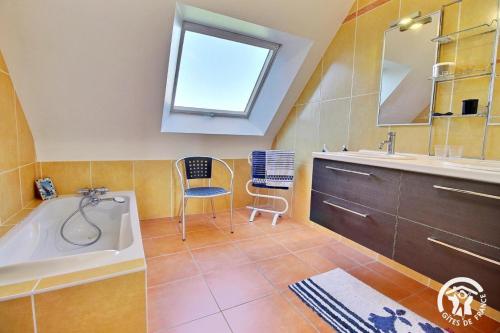 a bathroom with a tub and a sink and a chair at Les saudraies - unite familiale in Rieux
