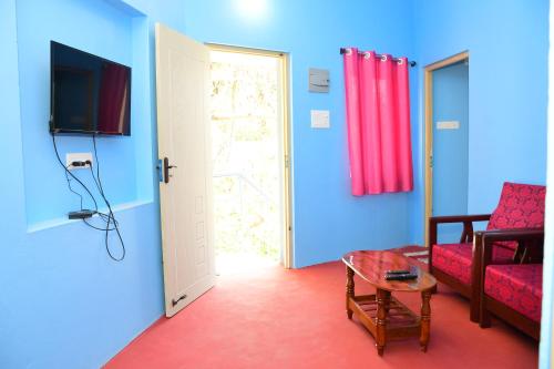 a living room with a couch and a table and a door at Greenfields Pondicherry- An Eco-friendly farm stay in Villianur