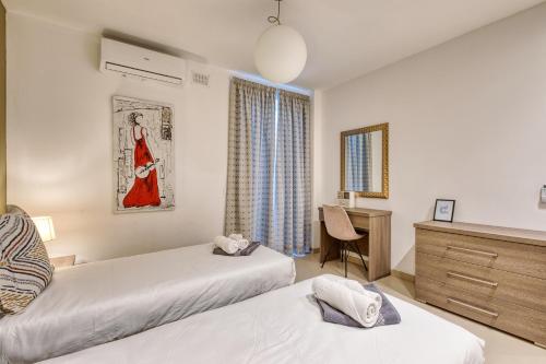 a bedroom with two beds and a desk and a window at Beautiful Penthouse with pool and terrace in Is-Swieqi