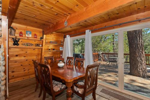 ein Esszimmer mit einem Tisch und einem großen Fenster in der Unterkunft Peaceful Sunshine Chalet with Hot Tub in Big Bear Lake