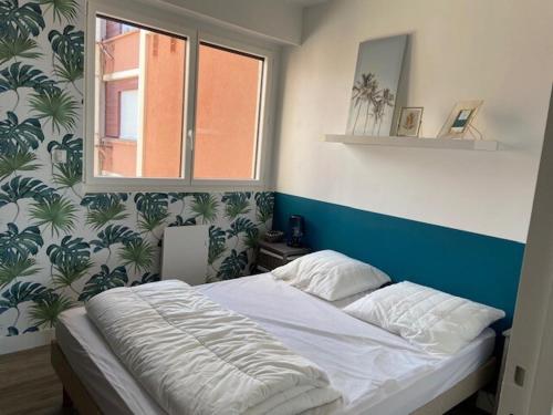 Ce lit se trouve dans une chambre dotée d'un mur bleu et blanc. dans l'établissement Tamaris 51, à Quend-Plage