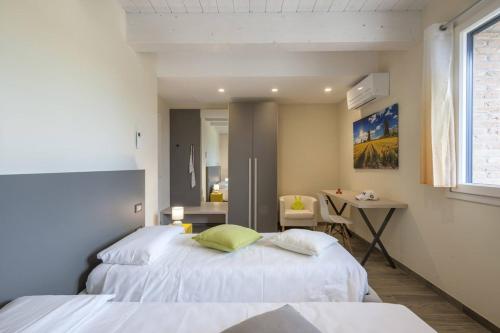 a bedroom with two beds and a desk and a window at Casale Astralis 13 by Marche Holiday Villas in Saltara