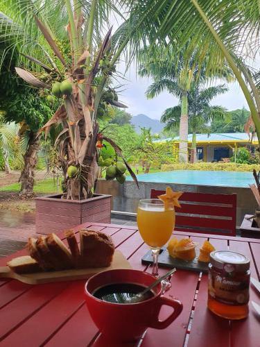 a table with a bowl of bread and a glass of orange juice at Le Paradis de la Guadeloupe in Pointe-Noire