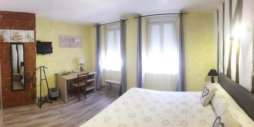 une chambre avec un lit, un bureau et des fenêtres dans l'établissement Hotel METROPOLE ET DE GASCOGNE, à La Celle-sous-Gouzon
