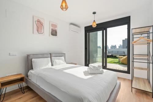 a bedroom with a bed and a large window at atico duplex con piscina y parking incluido ALQUILER TEMPORAL in San Sebastián de los Reyes