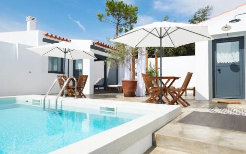 a pool with chairs and umbrellas next to a house at Casas da Praia - Casas da Amieira in Amieira