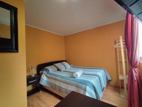 a small bedroom with a bed with yellow walls at HOSTAL LA CASONA ALFREDO CAMPOS in Ovalle