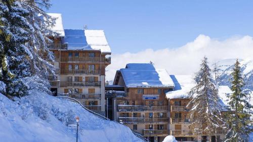 a building covered in snow in front of a mountain at Appartement - La Plagne - Les Coches - 7 Personnes - Pieds des pistes in La Plagne Tarentaise