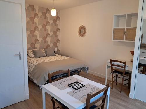 une petite pièce avec un lit, une table et des chaises dans l'établissement Studio 3 Cozy Proche du centre ville, à Rochefort