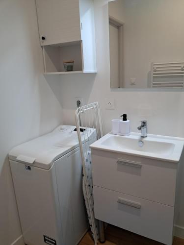 une salle de bain blanche avec un lavabo et un miroir dans l'établissement Studio 3 Cozy Proche du centre ville, à Rochefort