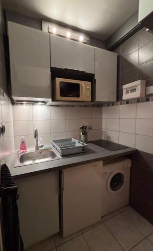 une cuisine avec un évier et un micro-ondes dans l'établissement La Clusaz Appartement 2 - 4 personnes, à La Clusaz