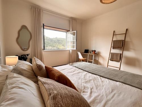 a bedroom with a bed and a window and a ladder at Casa Nabia - Surf & Nature in Ericeira