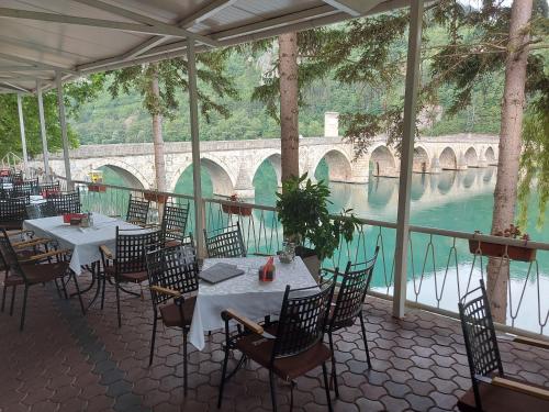 a restaurant with tables and chairs and a view of the water at Hotel Višegrad in Višegrad