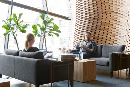 a man and woman sitting on couches in a living room at Stadthotel Brunner in Schladming