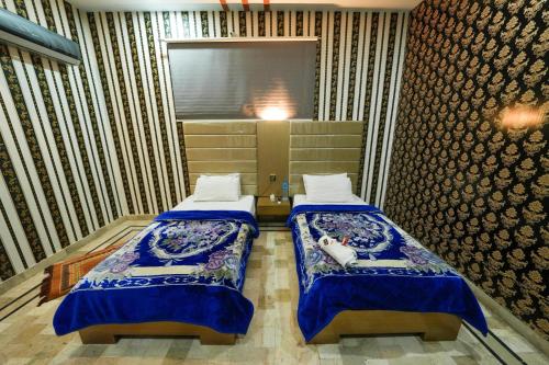 two beds in a room with blue and white at Hotel the Lodges inn in Multan