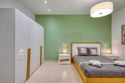 a bedroom with two beds and a green wall at Beautiful Penthouse with pool and terrace in Is-Swieqi