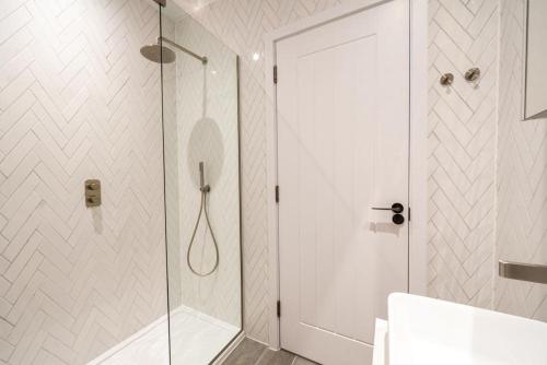 a white bathroom with a shower and a glass door at 3 Bedroom Luxury Waterside House in Hayle