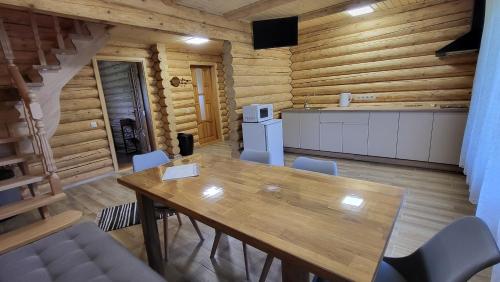 a dining table and chairs in a room with wooden walls at Котеджі Карпати Fest in Mizhhirʼʼya