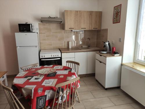 une cuisine avec une table avec des chaises et un réfrigérateur dans l'établissement Maisonnette rénovée à 5 mn du centre ville, à Cosne-Cours-sur-Loire