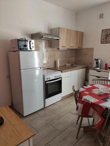 une cuisine avec un réfrigérateur blanc et une table dans l'établissement Maisonnette rénovée à 5 mn du centre ville, à Cosne-Cours-sur-Loire