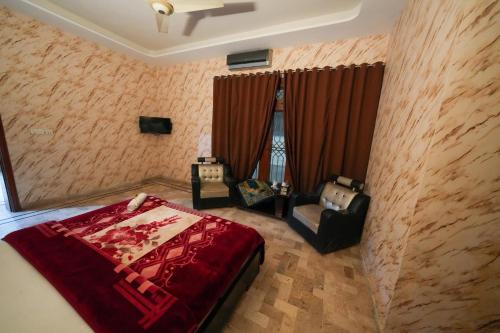 a bedroom with a bed and two chairs in it at Hotel the Lodges inn in Multan