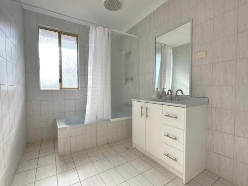 a bathroom with a tub and a sink and a mirror at Pelican Shore Villa 10 - Kalbarri WA in Kalbarri
