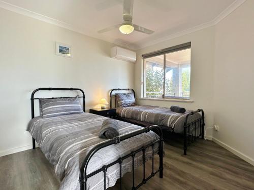 two beds in a room with a window at Pelican Shore Villa 10 - Kalbarri WA in Kalbarri