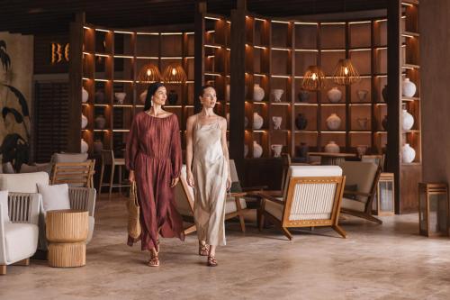 two women walking down the runway in a room with vases at Almare, a Luxury Collection Resort, Isla Mujeres, Adult All-Inclusive in Isla Mujeres